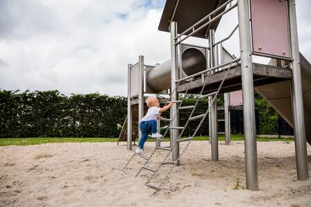 Kind klimt op een speeltoestel in een speeltuin op vakantiepark Topparken Park Westerkogge