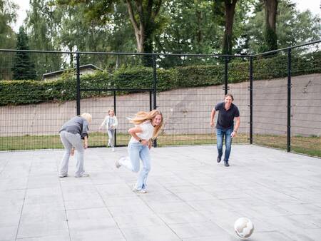 Kinderen voetballen op het speelveld van vakantiepark Topparken Recreatiepark de Wielerbaan
