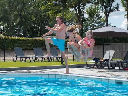 Mensen springen in het buitenbad van vakantiepark Topparken Recreatiepark de Wielerbaan