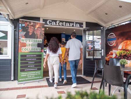 Gezin loopt de cafetaria binnen op vakantiepark Topparken Recreatiepark het Esmeer