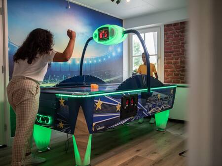 Mensen spelen airhockey in de gameroom van Topparken Recreatiepark het Esmeer