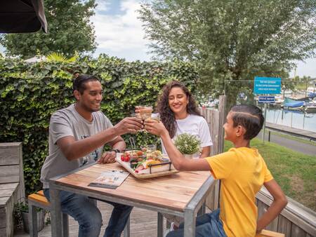 Gezin aan het eten op het terras van het restaurant op Topparken Recreatiepark het Esmeer