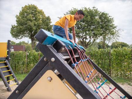 Jongen klimt op een speeltoestel in een speeltuin op Topparken Recreatiepark het Esmeer