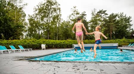 Twee kinderen springen in het buitenbad van vakantiepark Topparken Recreatiepark 't Gelloo