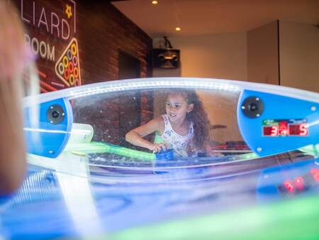 Kinderen spelen airhockey in de gameroom van vakantiepark Topparken Résidence De Leuvert