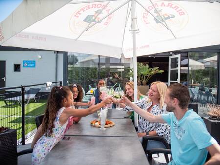 Gezin geniet van een drankje op het terras van het restaurant van Topparken Résidence De Leuvert