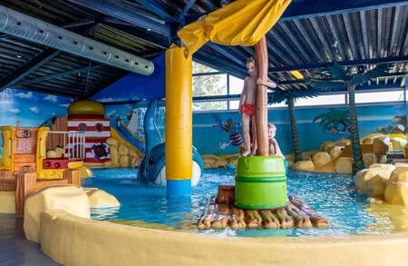 Kinderen bij speeltoestellen in het binnenbad van vakantiepark Bergumermeer