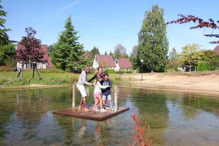Gezin op een vlot op een vijver in vakantiepark Hellendoorn