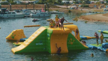 Kinderen op opblaasbare toestellen in het aquapark in de jachthaven van vakantiepark Leukermeer