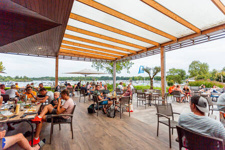 Mensen op het terras van Beachclub Leukermeer op vakantiepark Leukermeer