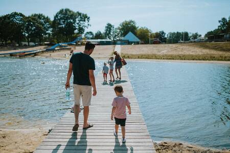 Gezin wandelt over een steiger door het recreatiemeer van Vakantiepark Wilsumer Berge