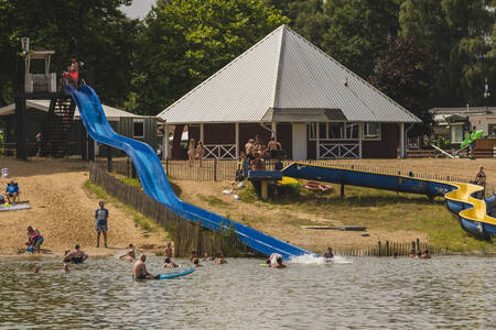 Mensen glijden van de glijbanen die uitkomen in het meer op vakantiepark Wilsumer Berge