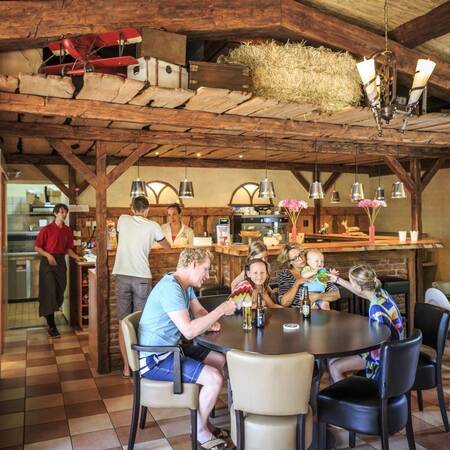 Gezin aan het drinken in het restaurant van Veluwecamping De Pampel