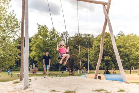 Kinderen spelen op een schommel in een speeltuin op Veluwepark de Bosgraaf