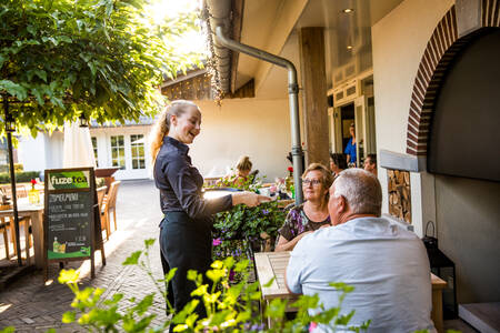 Mensen op het terras van Restaurant De Hazelaer op Villapark Hof van Salland